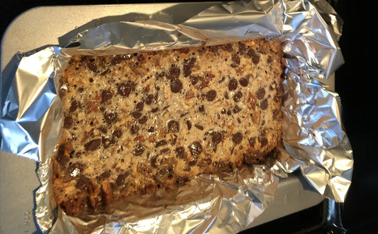 Chocolate pecan bars in foil-lined baking pan with buttery shortbread crust and gooey chocolate pecan topping