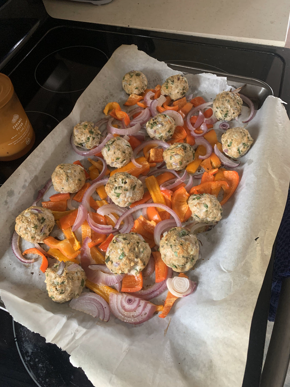 Golden turkey meatballs with roasted red and orange bell peppers and caramelized onions on a sheet pan