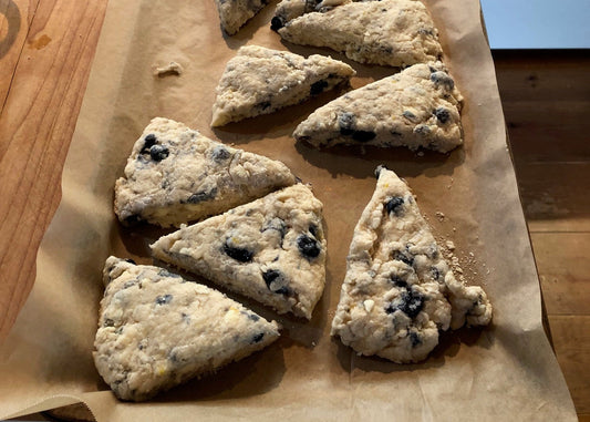 Golden brown lemon blueberry scones with fresh blueberries and flaky texture on a rustic surface