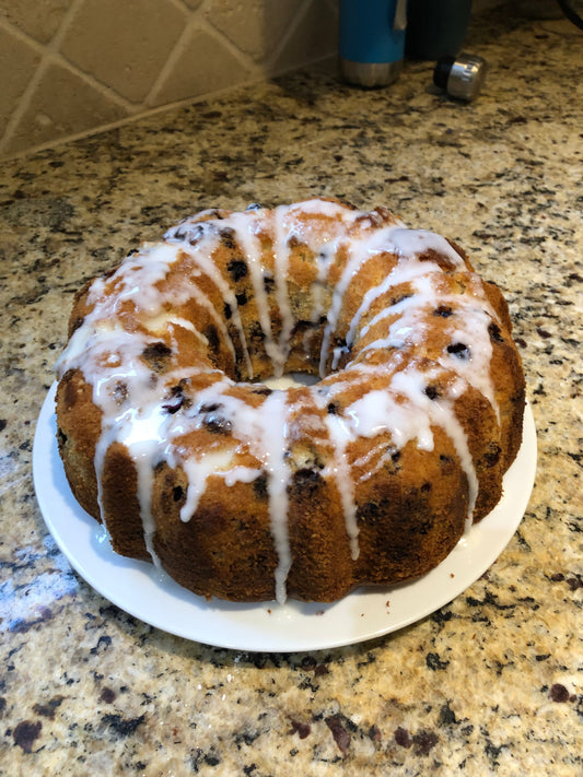 Lemon blueberry Bundt cake drizzled with icing on a plate on a counter