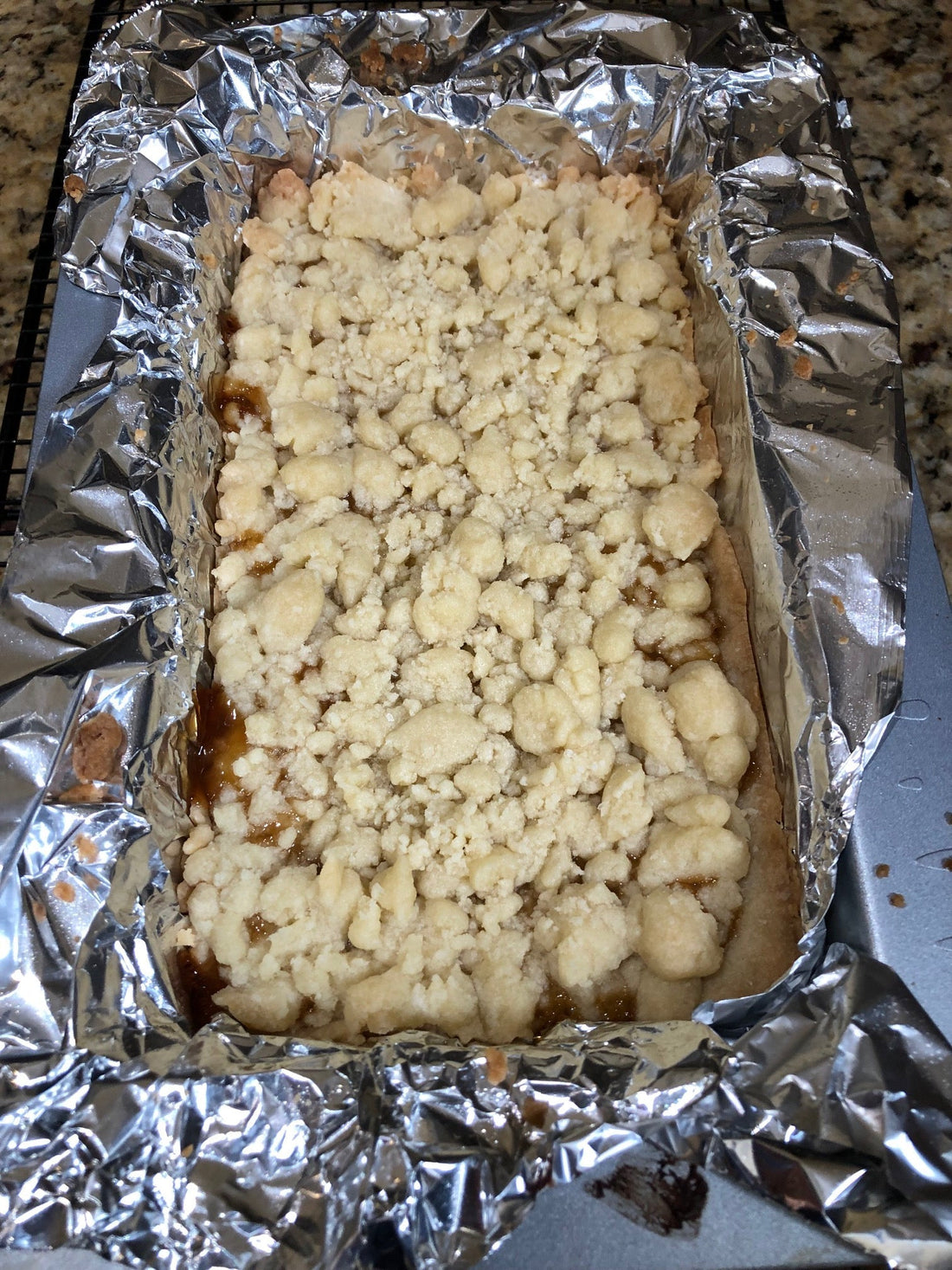 Overhead view of salted caramel bars in pan lined with tin foil