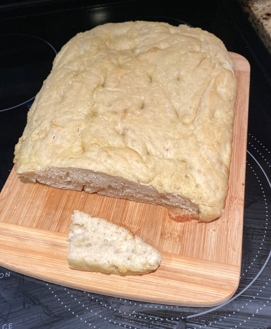 Golden baked focaccia bread with dimpled surface and olive oil