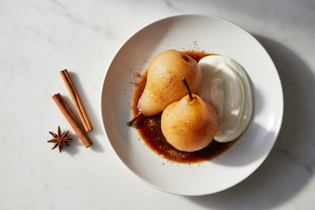Two whole Ceylon cinnamon poached pears on a ceramic plate, translucent and golden-amber, drizzled with reduced spiced syrup and a dusting of cinnamon — a metabolic-friendly dessert from The Spice Apothecary.