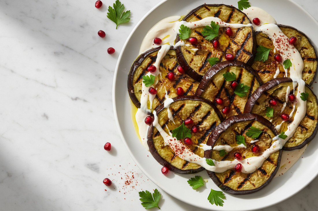 Grilled eggplant rounds on a platter with tahini sauce, pomegranate seeds, fresh parsley, and sumac