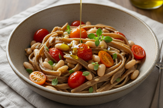 Bowl of whole grain pasta with white beans, cherry tomatoes, and fresh oregano drizzled with olive oil