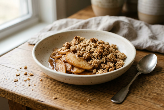 A spooned serving of homemade apple crisp with tender apple slices and a golden oat crumble topping in a cream bowl.